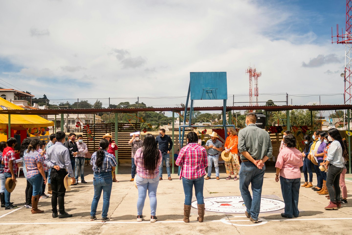 Adults in a community meeting on an outdoor court.